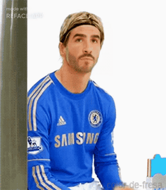 a man wearing a blue samsung jersey is sitting in front of a wall