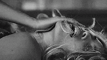 a black and white photo of a woman laying on her stomach with her hand on her face .