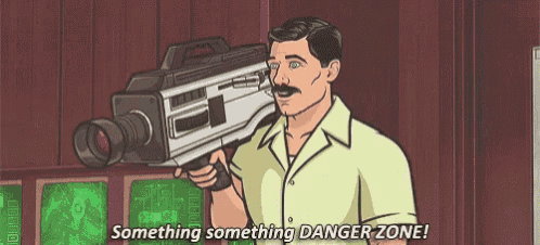 a man is holding a camera in his hand and saying `` something something danger zone '' .