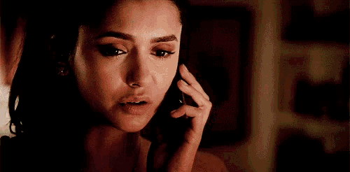 a man is talking on a cell phone while sitting in a dark room .