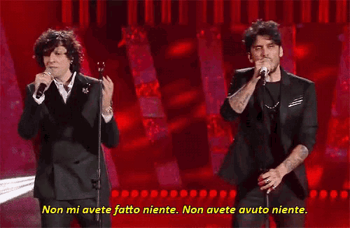 two men singing into microphones with the words non mi avete fatto niente written below them