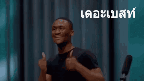 a man in a black shirt is giving a thumbs up sign in thai .
