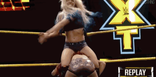 a woman is wrestling another woman in a ring with a replay button