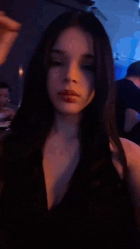 a woman in a black dress is adjusting her hair in a blurry photo