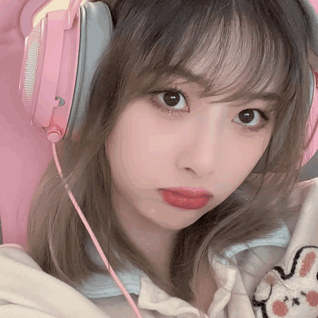 a close up of a woman wearing headphones with a pink cord