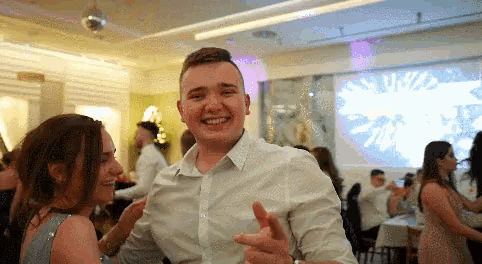 a man in a white shirt is smiling while dancing with a woman