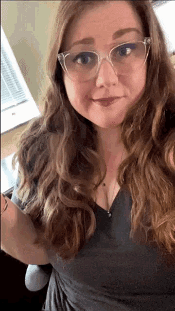 a woman wearing glasses is taking a selfie in front of a window