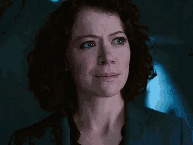 a woman with curly hair is crying and making a sad face .