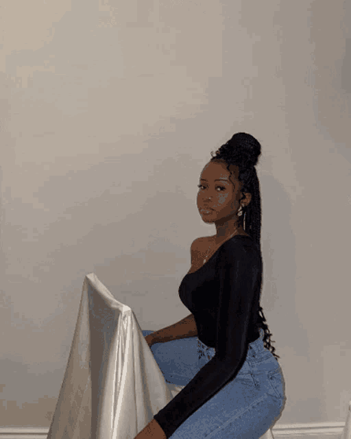 a woman in a black top and blue jeans is kneeling down