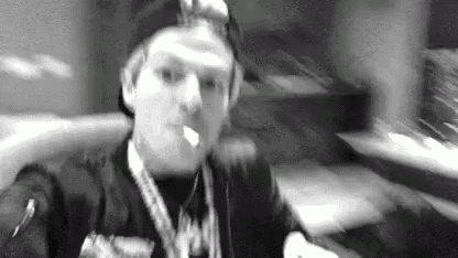 a black and white photo of a man smoking a cigarette in a room .
