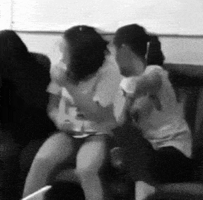 a group of people are sitting on a couch and fighting .