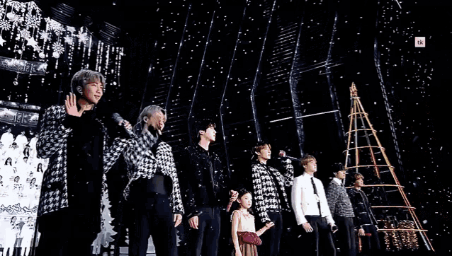 a group of people standing next to each other on a stage holding microphones .