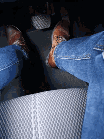 a person wearing brown shoes is pressing the brake pedal of a car