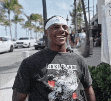 a man wearing a bakuganma t-shirt smiles on the street