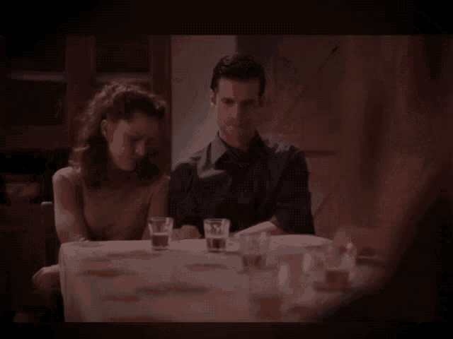 a man and a woman sit at a table with a child standing behind them