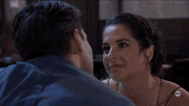 a man and woman are kissing in front of a bar with a bottle of vodka in the background