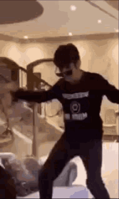 a man wearing sunglasses and a black shirt is dancing in a living room .
