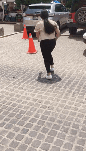 a woman is walking down a cobblestone street next to a jeep with a license plate that says nc-88