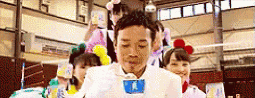 a group of people are standing around a man in a white suit holding a cup of ice cream .