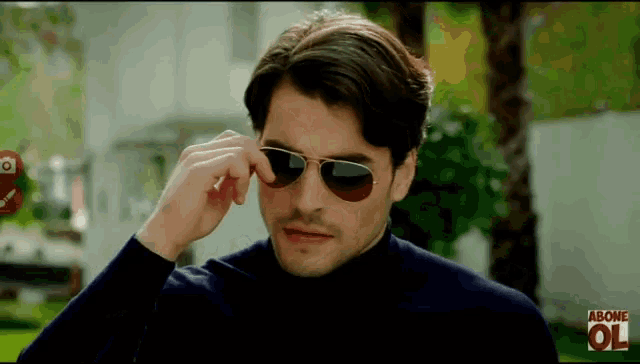 a man wearing sunglasses has above ol written on the bottom of his screen