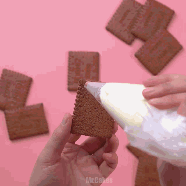 a person is holding a piece of chocolate biscuit and icing is being poured on it