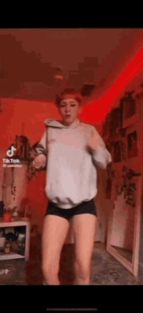 a girl is dancing in a room with a red light behind her
