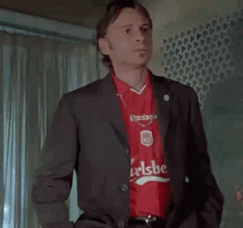 a man in a suit and a red shirt is giving a thumbs up .