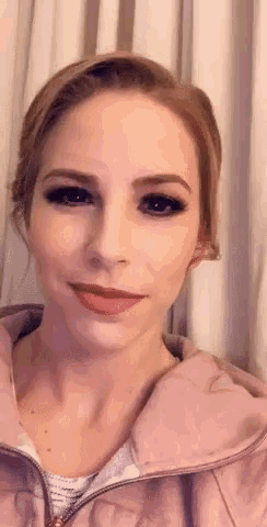 a close up of a woman 's face in front of a white curtain .