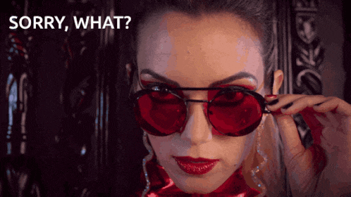 a woman wearing red sunglasses with the words sorry what behind her