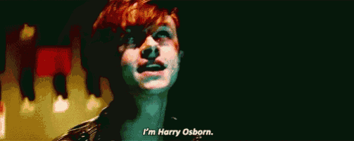 a young man with red hair is standing in a dark room and saying `` i 'm harry osborn . ''