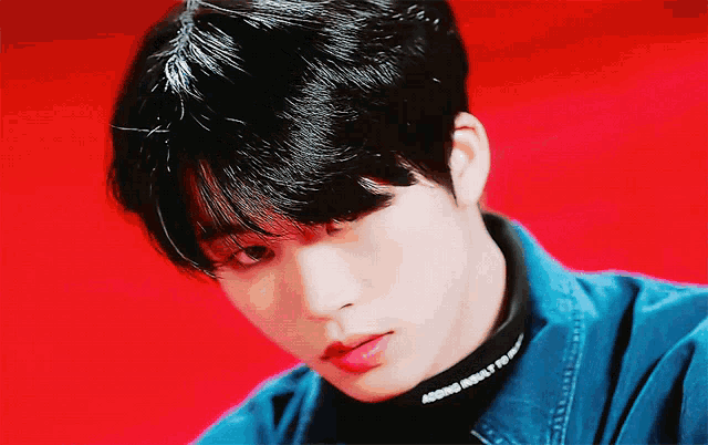 a close up of a young man wearing a denim jacket and a black turtleneck that says adding impact to life