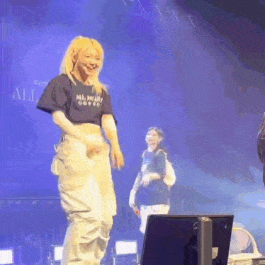 a woman is dancing on a stage while another woman looks on .