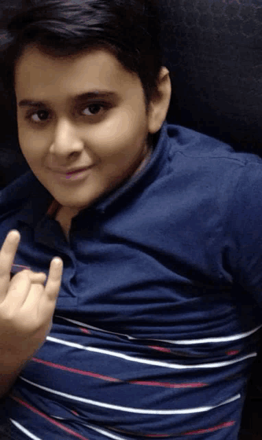 a young boy wearing a striped shirt is giving the middle finger