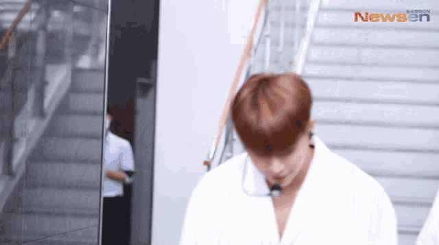 a man in a white shirt is walking down stairs in front of a newsen logo