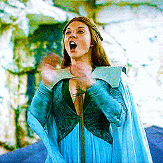 a woman in a blue dress is singing into a microphone with her mouth open .
