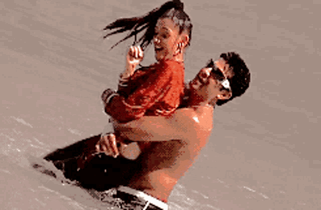 a man is carrying a woman in his arms on a beach