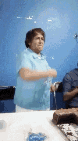 a woman in a blue shirt is sitting at a table with a cake