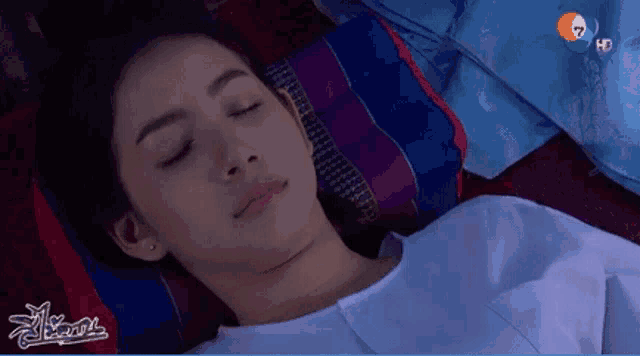 a woman is laying on a bed with her eyes closed in front of a sign that says ' a ' on it