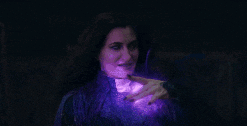 a woman is standing in a dark room with purple smoke coming out of her mouth .