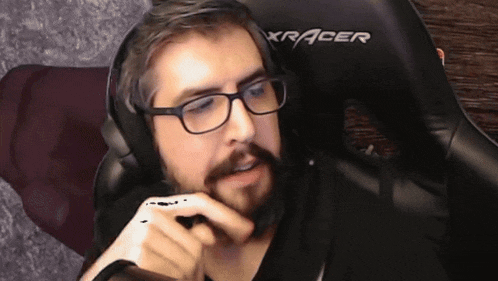 a man wearing glasses and headphones is sitting in a chair that says xracer