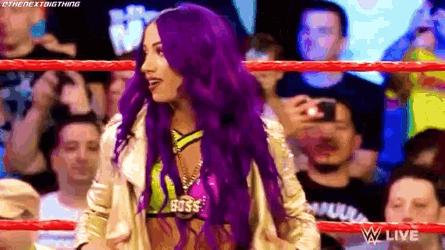 a woman with purple hair is in a wrestling ring .