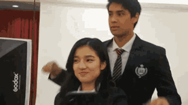 a man in a suit and tie is standing next to a woman in a suit .