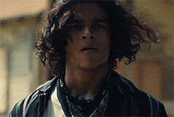 a young man with long curly hair wearing a bandana around his neck