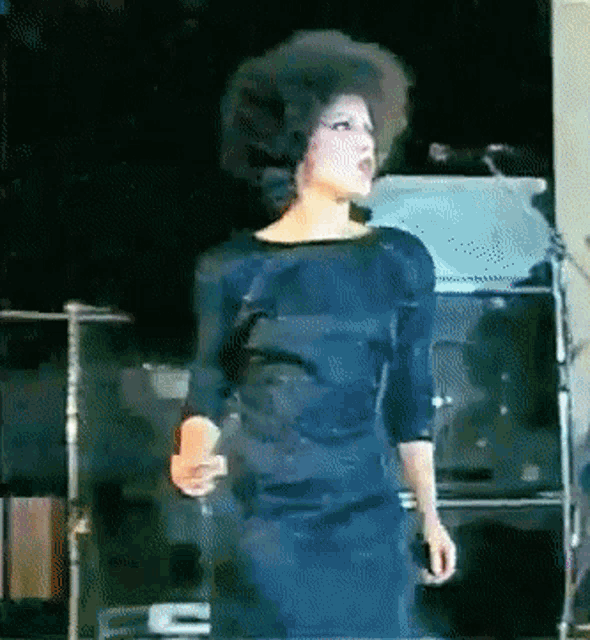 a woman in a blue dress is standing in front of a microphone that says ' fender ' on it