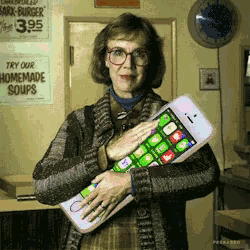a woman holding a cell phone in front of a sign that says homemade soups