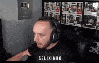 a man wearing headphones is sitting in front of a shelf full of funko pop figures ..