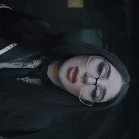 a woman wearing glasses and a black shirt has a tattoo on her chest
