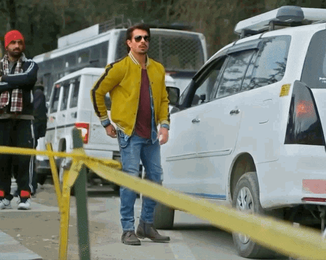 a man in a yellow jacket is standing next to a white van