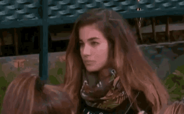 a woman with long hair and a scarf around her neck is looking at the camera .