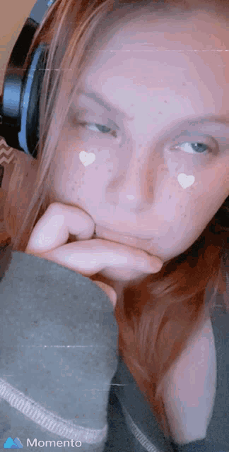 a woman wearing headphones has hearts painted on her face and the word momento on the bottom